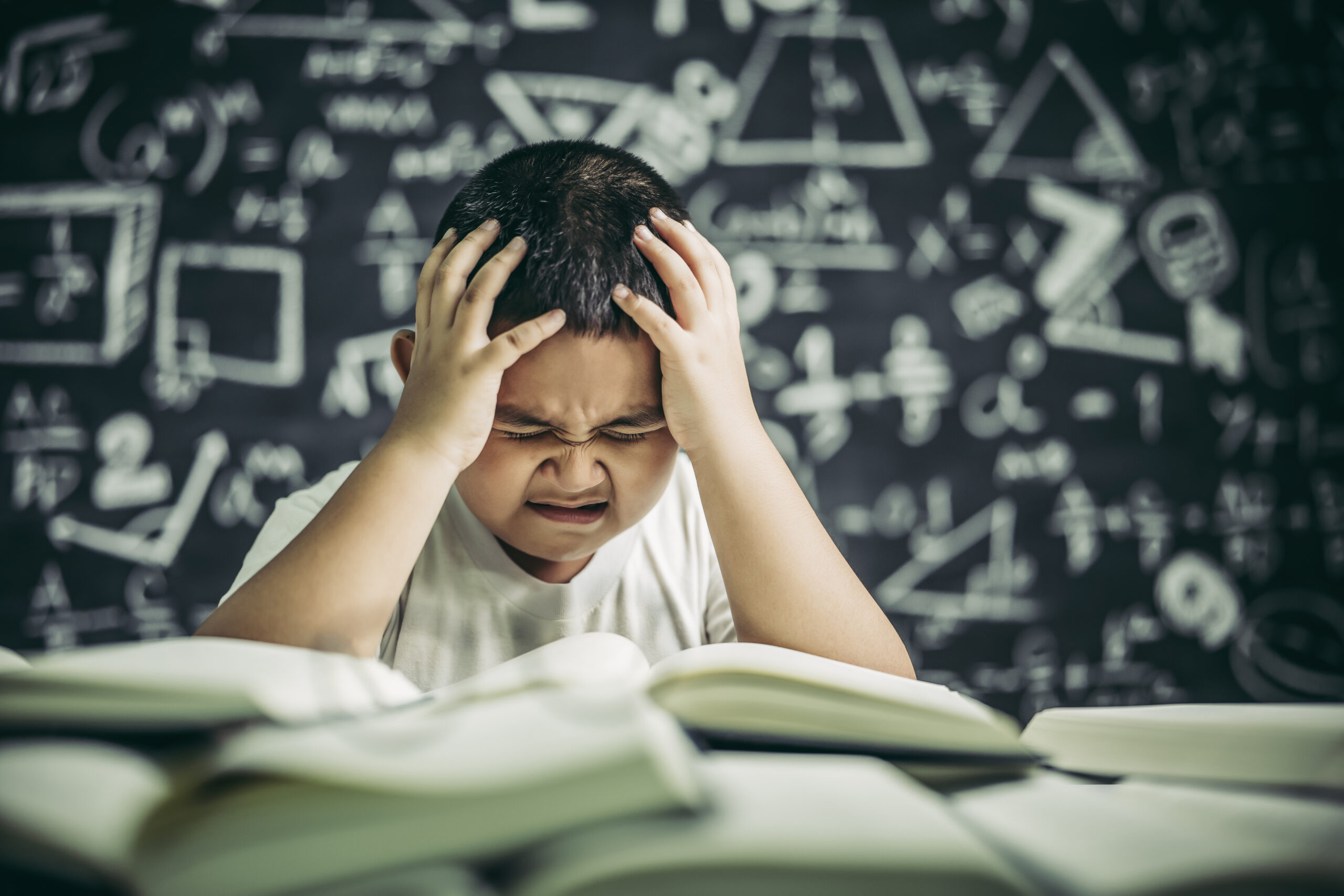 Boys with glasses write books and think in the classroom