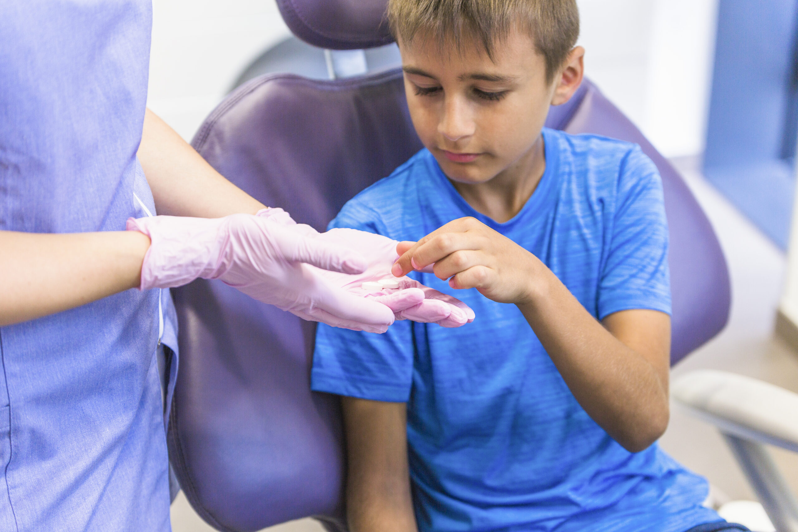 child-patient-taking-medicine-from-female-dentist-hand